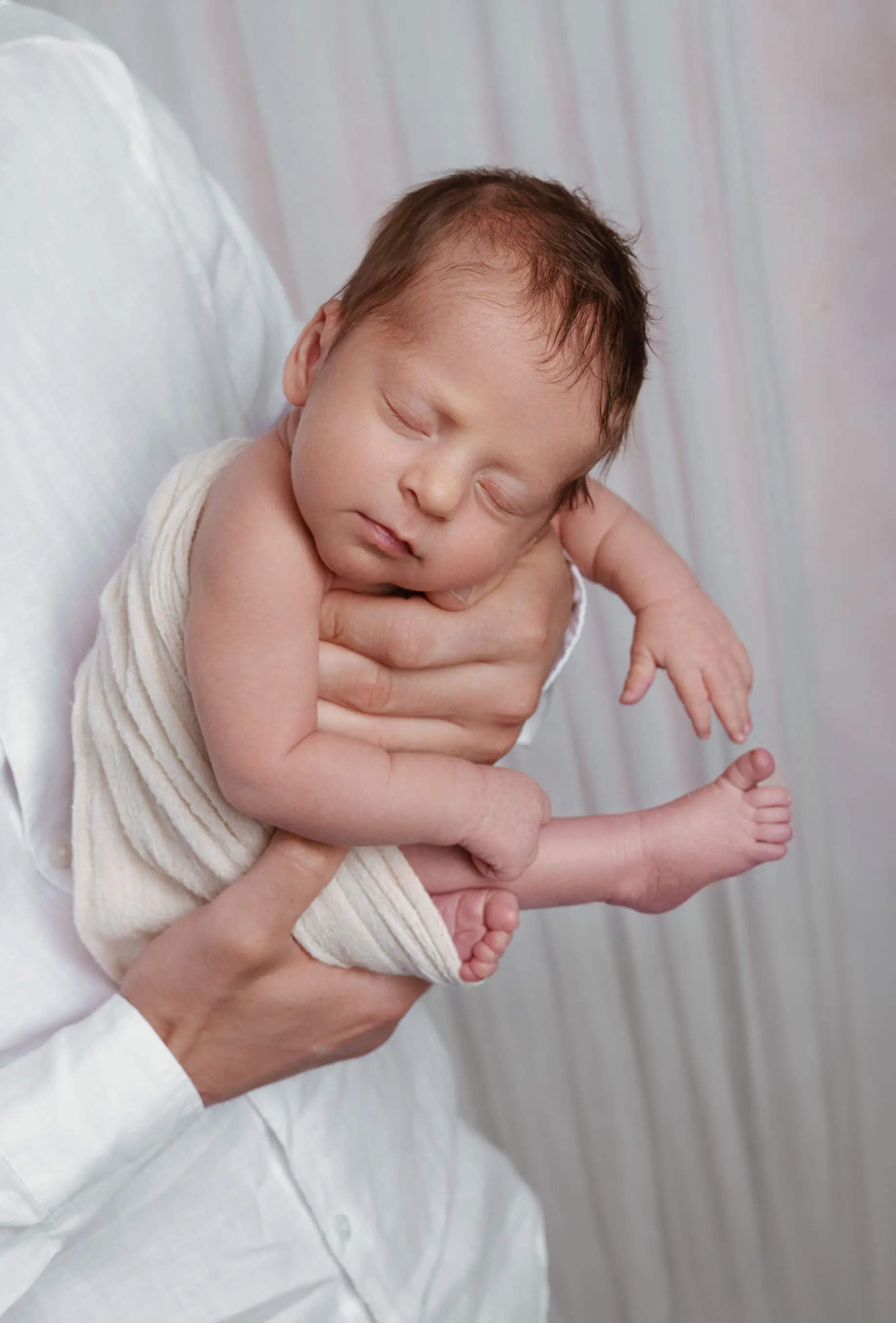 Newborn baby sleeping in a soft at-home photography setup